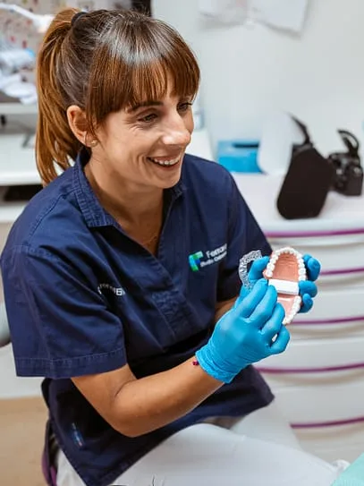 La Dr.ssa Irene Ferrara mostra un modello dentale sorridendo in studio